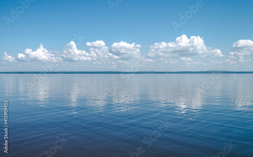 Landscape of calm lake, blue sky with clouds reflected in the water