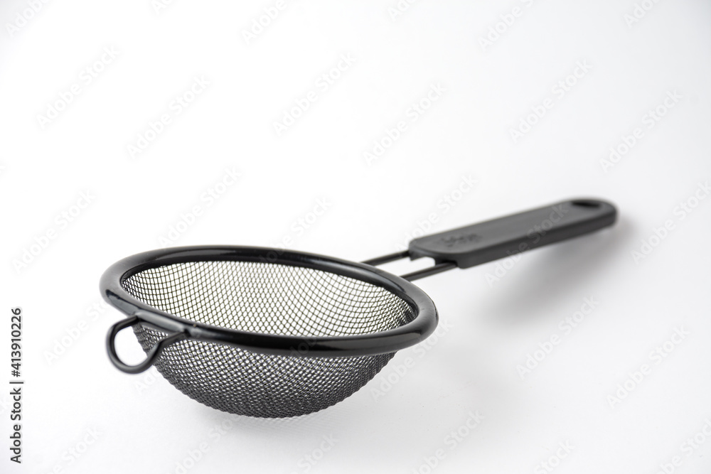 Close-up of black metal strainer, on white background, horizontal, with copy space Close-up of black metal strainer, on white background, horizontal, with copy space