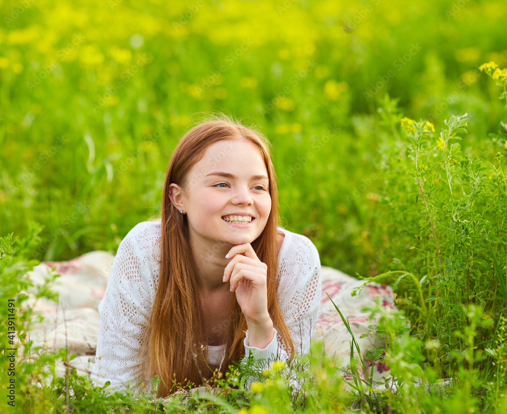 Beautiful red hair woman lying on grass at the park on summer day Beautiful red hair woman lying on grass at the park on summer day