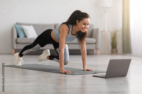 Active woman doing fitness at home  using laptop