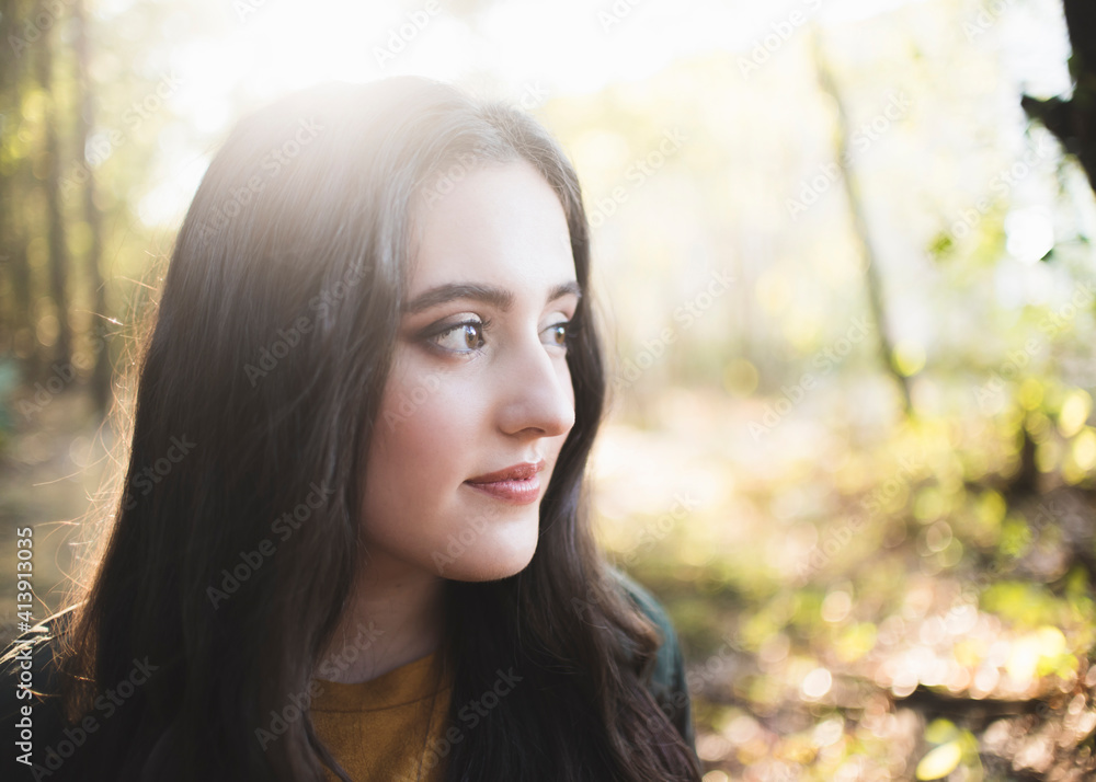 Close-up of thoughtful teenage girl with long hair looking away while standing in forest