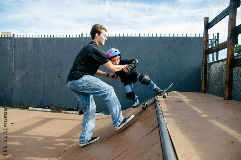 Skateboarding instructor helps student grind on half pipe Skateboarding instructor helps student grind on half pipe