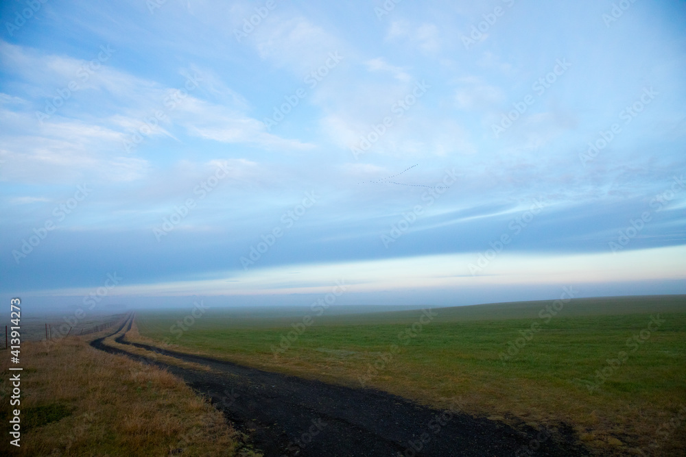 early morning view of sky and country road through fields in Iceland early morning view of sky and country road through fields in Iceland