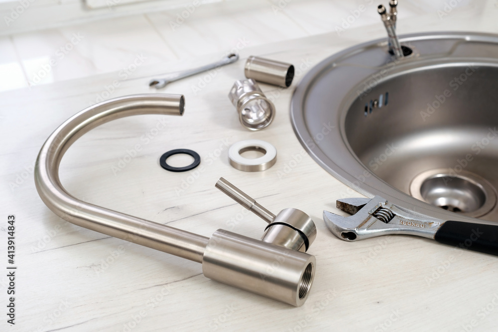 New faucet and adjustable wrench for installing into the kitchen sink, plumbing work or renovation. Selective focus New faucet and adjustable wrench for installing into the kitchen sink, plumbing work or renovation. Selective focus