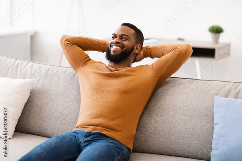 Happy African American Man Relaxing Sitting On Sofa At Home