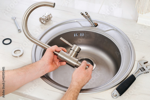 Close-up plumber hands holds a new faucet for installing into the kitchen sink, plumbing work or renovation