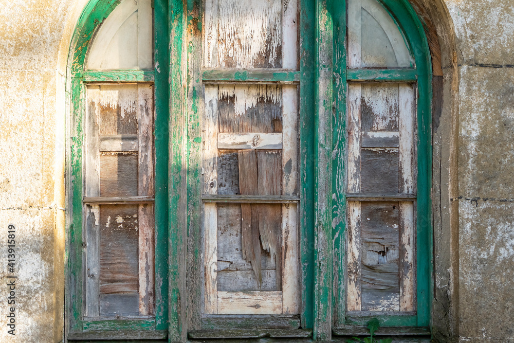 An old arched wooden window boarded up with cracked plywood An old arched wooden window boarded up with cracked plywood