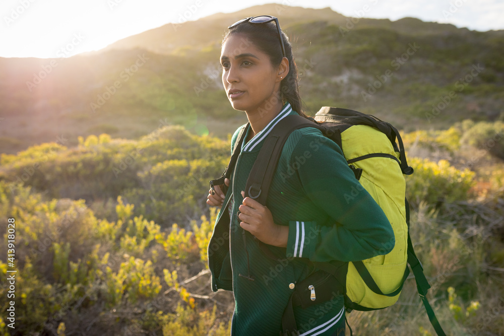 Mixed race woman wearing a backpack and hiking in mountains by the coast Mixed race woman wearing a backpack and hiking in mountains by the coast