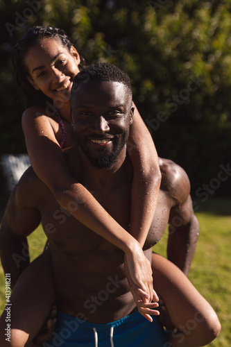 Portrait of two diverse male and female friends man carrying on back and smiling