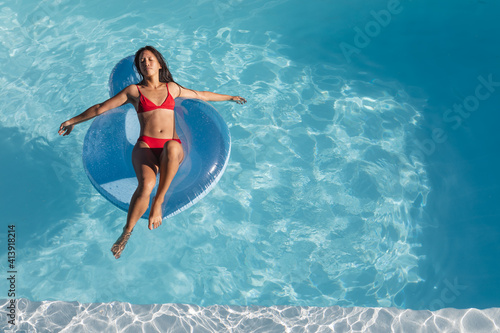 Mixed race woman sunbathing on inflatable in swimming pool