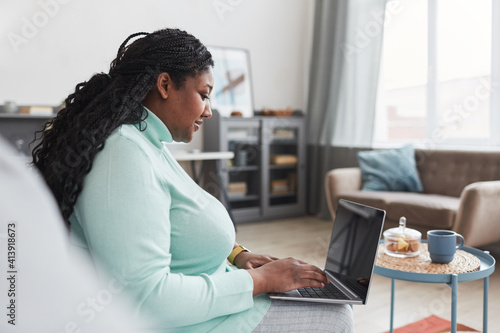 Vászonkép Side view at curvy African American woman using laptop while working from home s