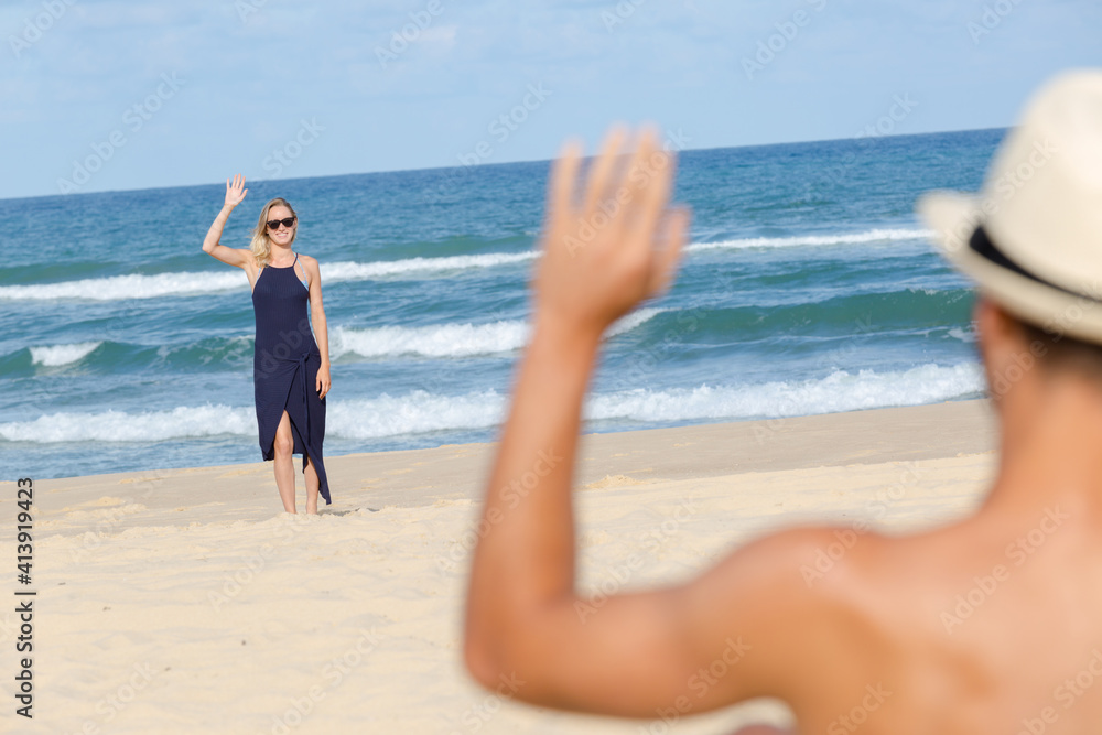couple waving to each other across the beach couple waving to each other across the beach