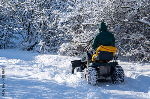person in snow, man driving a snow plow tractor in a winter landscape, way with snow