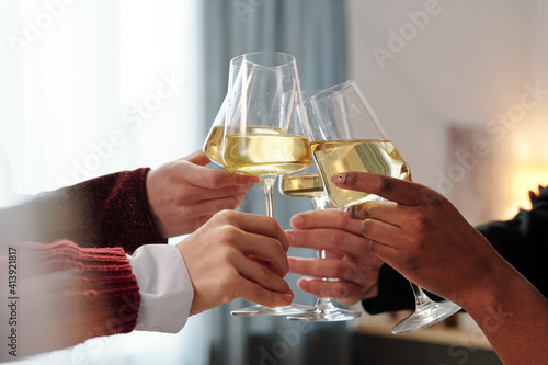 Hands of young friends or business people clinking with flutes of champagne