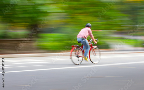 Bike rider moving fast with motion blur wearing pink © Mark