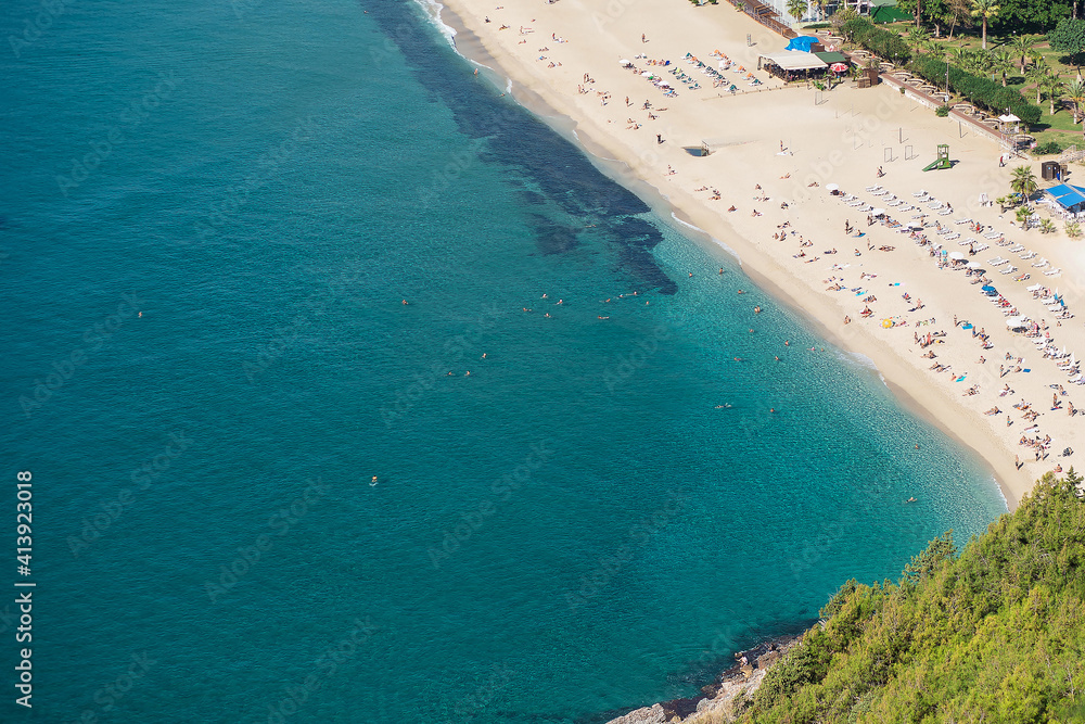 View from above to the beach with people and turquoise sea. Holiday season vacation concept.