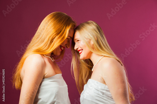 Two women standing opposite each other  touching by heads