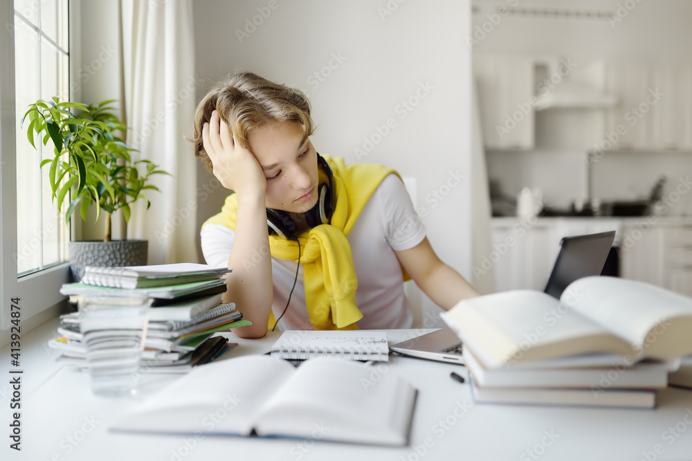 Teenager boy study at home. Online education and distance learning for children. School boy doing his physics homework using gadgets. Lessons on the internet for high school students