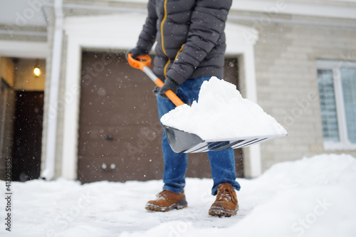 Wall Mural A mature man clean path near house from snow during strong blizzard