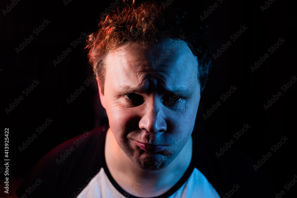 Portrait funny and crazy man and mustache in studio on black background. Crazy face grimacing on red and blue light.