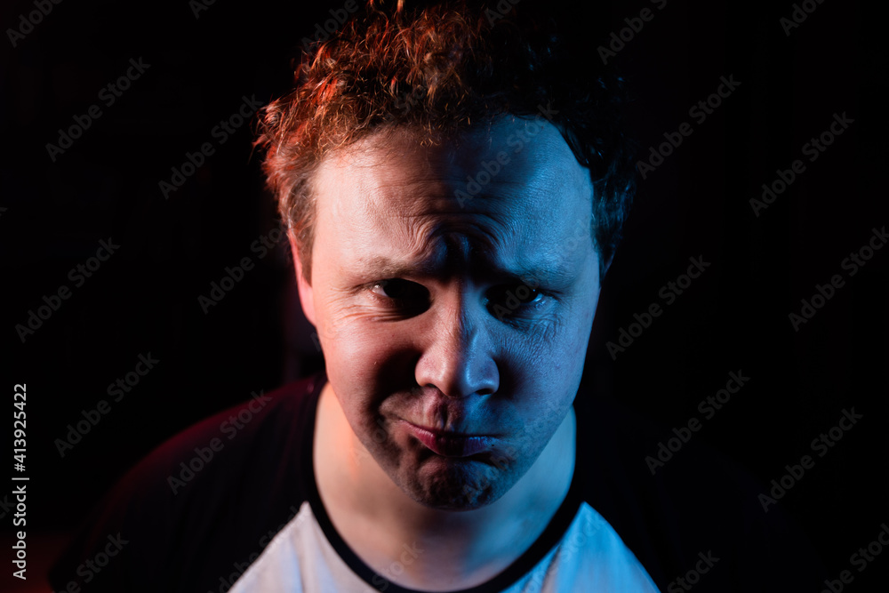 Portrait funny and crazy man and mustache in studio on black background. Crazy face grimacing on red and blue light. Portrait funny and crazy man and mustache in studio on black background. Crazy face grimacing on red and blue light.