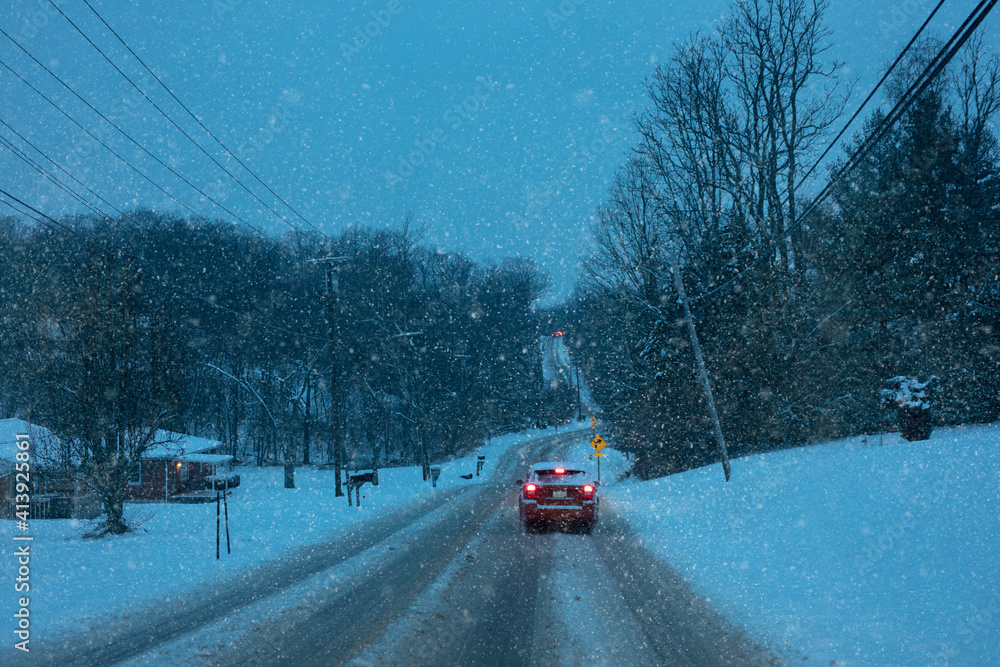 Car driving on snow covered road in bad weather conditions.