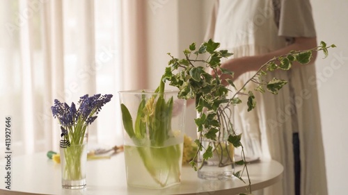 Mujer al costado de la mesa con variedad de jarrones con flores