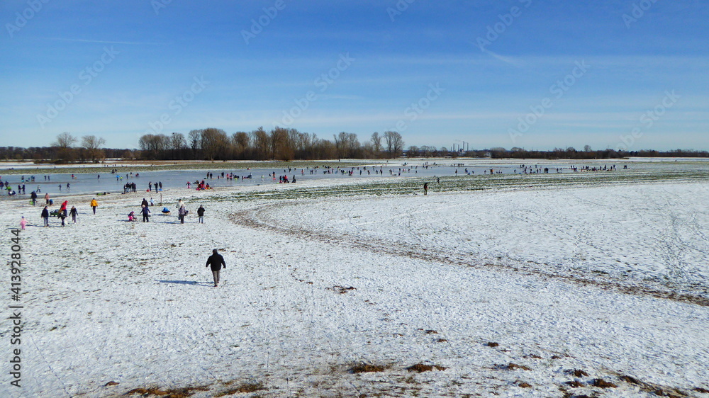 Auf den zugefrorenen Rheinwiesen im Uedesheimer Rheinbogen laufen viele Leute Schlittschuh. Nach leichtem Hochwasser und kalten Temperaturen locken schöne glatte Eisflächen viele Besucher an.