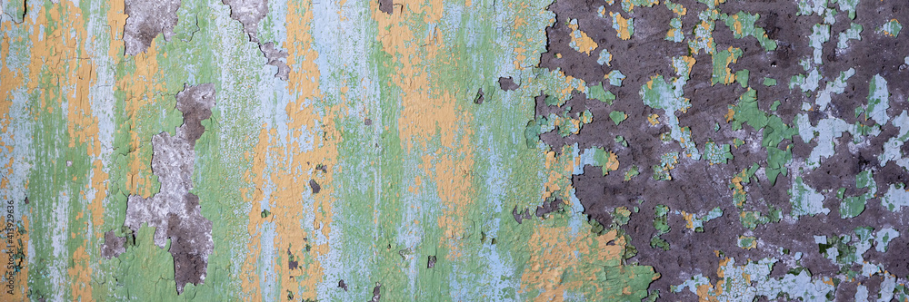 Peeling paint on the wall. Panorama of a concrete wall with old cracked flaking paint. Weathered rough painted surface with patterns of cracks and peeling. Wide panoramic texture for design background