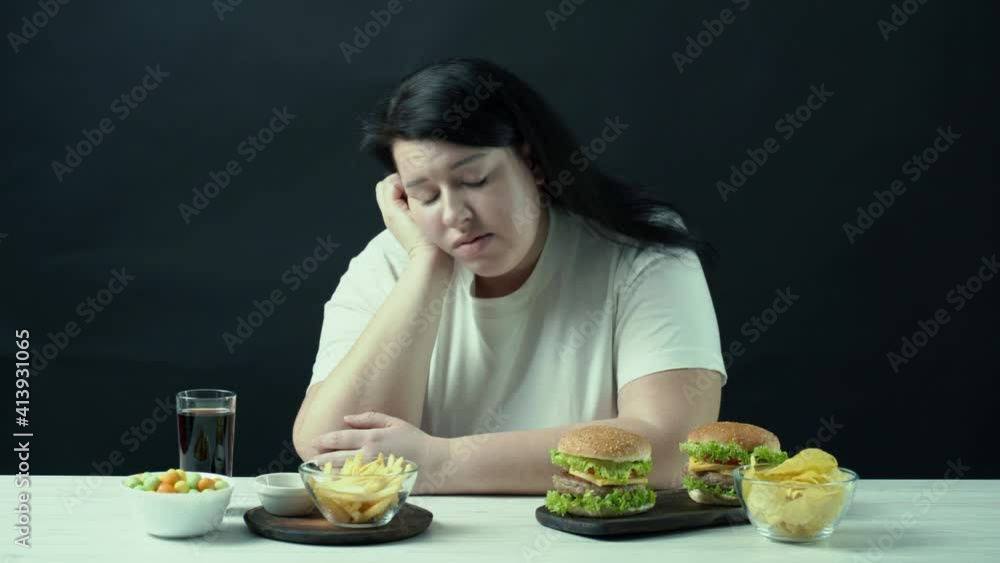 Young upset overweight woman tired of diets with junk food. Dieting restricts, compulsive overeating, unhealthy eating Young upset overweight woman tired of diets with junk food. Dieting restricts, compulsive overeating, unhealthy eating