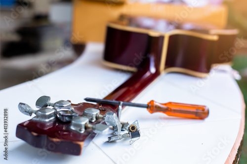 Selective focus to broken guitar with screwdriver to repairing guitar in guitar repair shop.