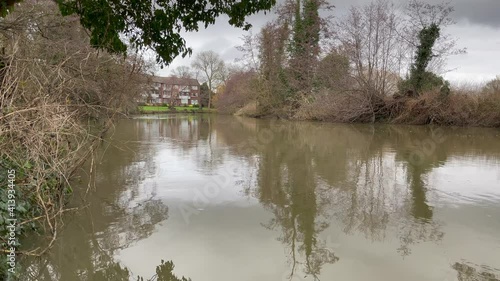 Landscape shot of a murky river in the winter on a cloudy day, river surrounded by woodland. photo