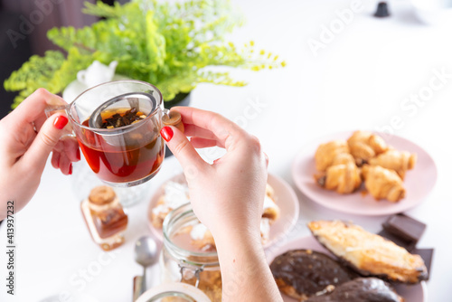 White woman hands with red nails, Cup of Tea, on white background with chocolate Tablet, croissant, chocolate puff pastry, sugar puff pastry, whole grain panela