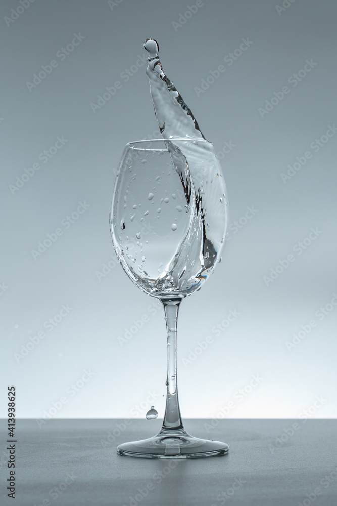 Splash of water in a glass on a gray background. Splash of water in a glass on a gray background.