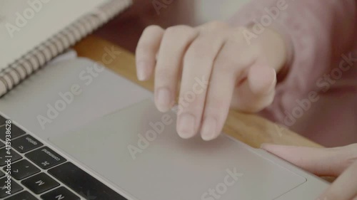 Close Up hand on a Laptop Computer. Device is Used on a Kitchen Table in a Modern Home. Person Uses Touch Pad. photo