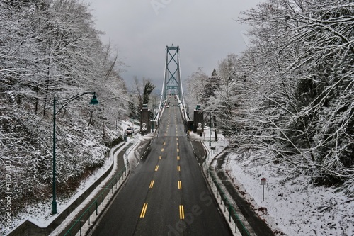 Suspension bridge over the ocean bay in winter. Lions gate bridge in a foggy snowy day between Stanley park and North Vancouver. British Columbia. Canada  photo