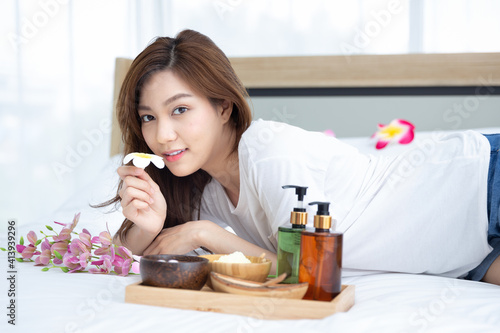 Young Asian women are enjoying the preparation of spa equipment. Smiling young girl waiting for a DIY home spa treatment in her white bedroom.