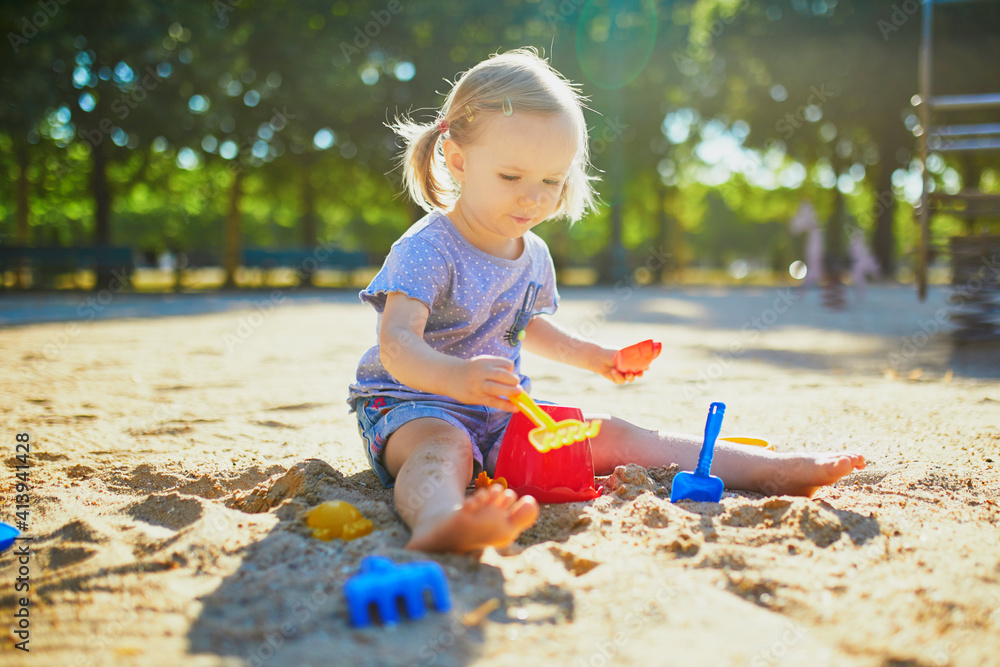 Adorable little girl having fun on playground in sandpit Adorable little girl having fun on playground in sandpit
