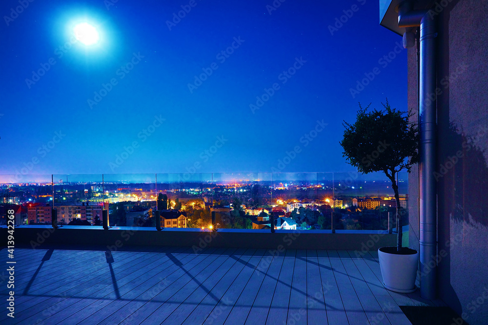 cozy rooftop patio area in the moonlight with night city view