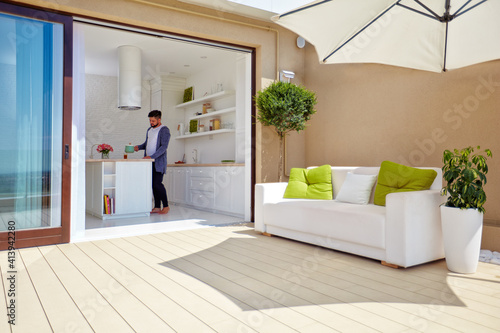 Obraz na plátně man cooking on cozy open space kitchen with rooftop patio and sliding doors