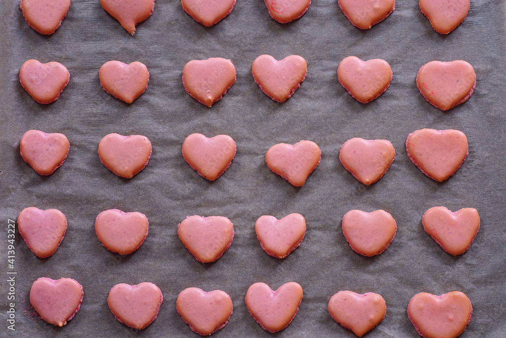 Obraz premium Pink heart homemade macaron cookies on parchment paper on a baking sheet