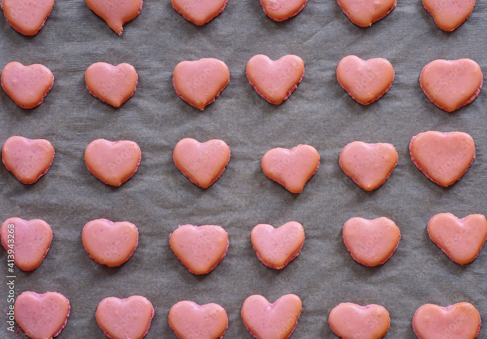Obraz premium Pink heart homemade macaron cookies on parchment paper on a baking sheet