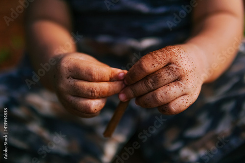 the boy's hand was playing on the dirty ground