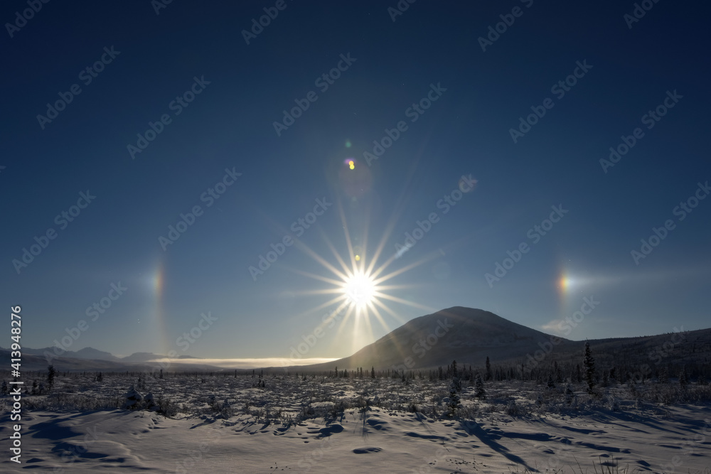 Ice crystals in the atmosphere create a halo around the sun with sun dogs to the left and right. Ice crystals in the atmosphere create a halo around the sun with sun dogs to the left and right.