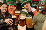 Group of happy football fans in traditional irish attire clinking with beer