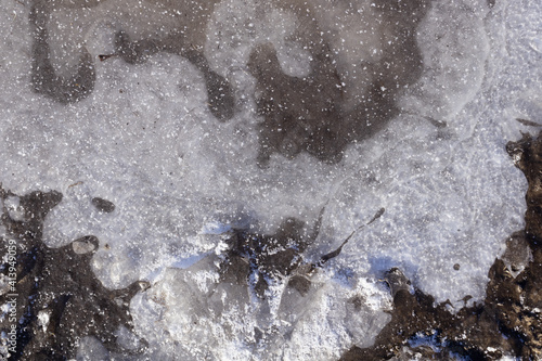 an air bubble under a frozen puddle forms a white pattern and cracked in one place