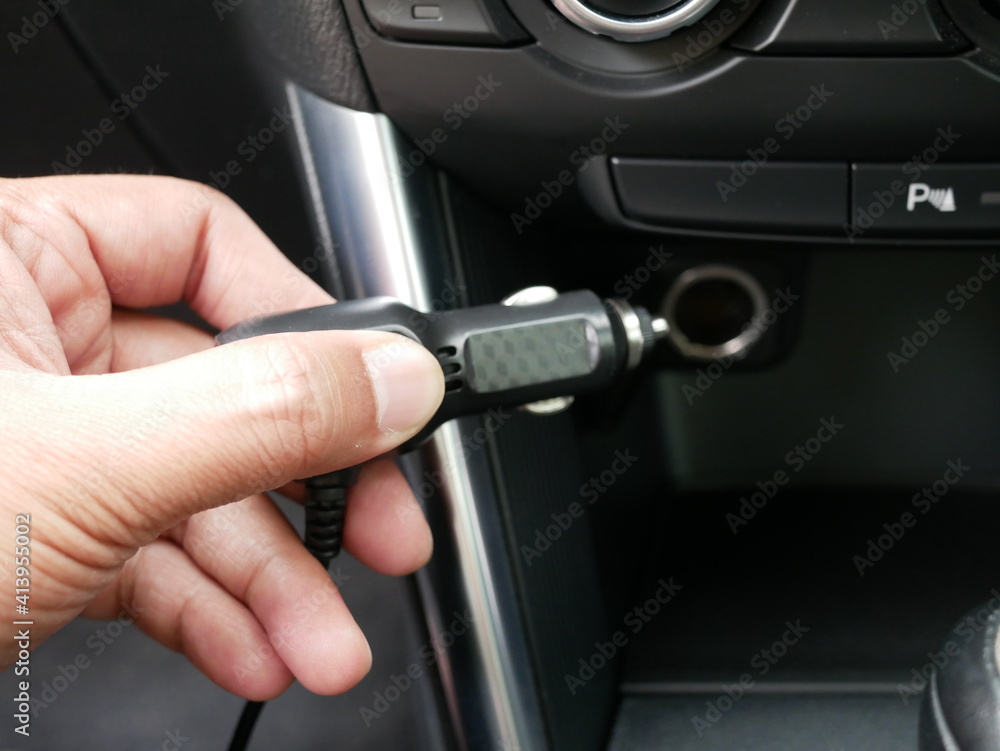 hand holding plug 12 volt into socket from car cigarette lighter.