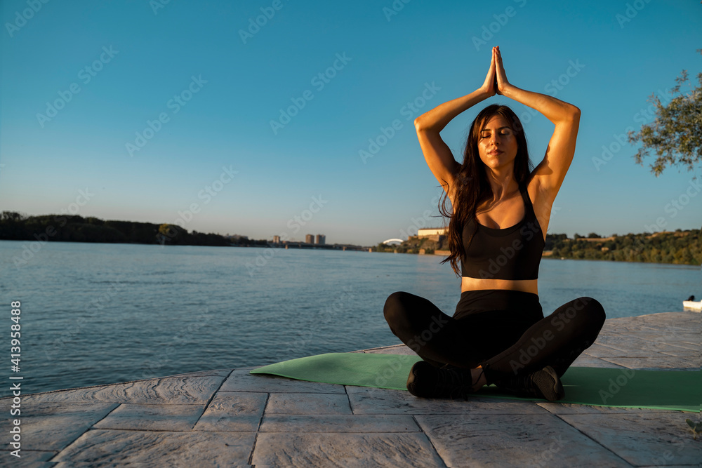 Young woman performing yoga, meditation, by the river 