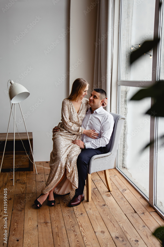 Pretty young couple in elegant clothes tenderly hugging and kissing each other in modern hotel room. Romantic date of couple in love in classic interior. Happy hugs of young family. Man and woman Pretty young couple in elegant clothes tenderly hugging and kissing each other in modern hotel room. Romantic date of couple in love in classic interior. Happy hugs of young family. Man and woman