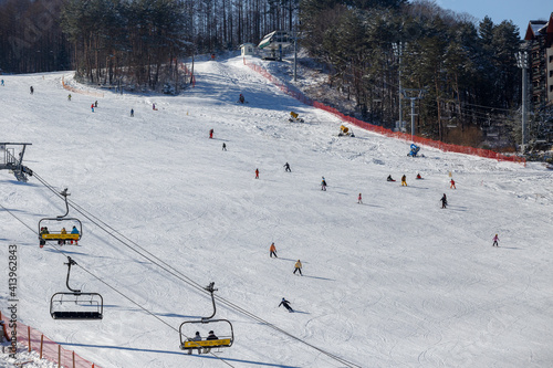 Alpencia, South Korea, 2016 - Olympic Village for the 2018 Winter Olympics. Tourists ski and snowboard on a beautiful snowy slope of the ski slope photo